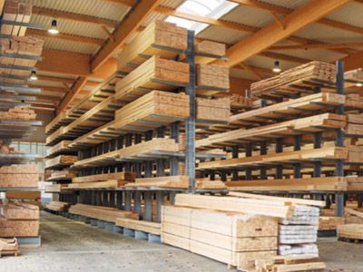 Gro&szlig;es Lagerhaus mit gestapelten Holzbrettern auf Metallregalen unter hohem Dach mit Oberlichtern.