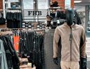 Arbeitskleidungsgesch&auml;ft mit schwarzen Kleiderst&auml;ndern und Schaufensterpuppe im Vordergrund