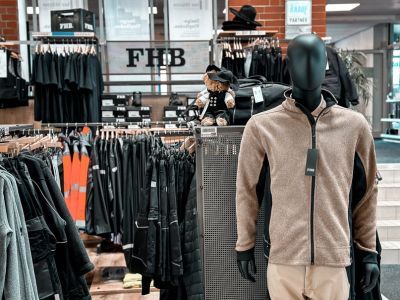 Arbeitskleidungsgesch&auml;ft mit schwarzen Kleiderst&auml;ndern und Schaufensterpuppe im Vordergrund