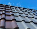 Dachziegel in Braun und Grau installiert unter blauem Himmel, zeigt Auswahl an Materialien f&uuml;r Dachdeckung