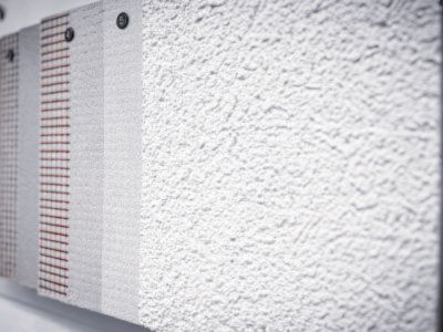 Wand zeigt verschiedene Putzmuster mit glatten und rauen Texturen, befestigt zur Ansicht und Auswahl.