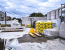 Baustelle mit Paletten voller Zements&auml;cke und Porenbetonbl&ouml;cken, Hubwagen steht bereit unter Wolkenhimmel.