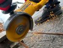 Winkelschleifer schneidet Metallrohr, Funken fliegen &ndash; zeigt Einsatz von Maschinen im Bauhandwerk.