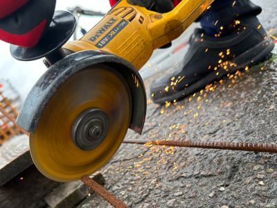 Winkelschleifer schneidet Metallrohr, Funken fliegen &ndash; zeigt Einsatz von Maschinen im Bauhandwerk.