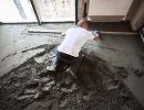 Eine Person gl&auml;ttet frischen Betonboden &ndash; zeigt Arbeitsschritte beim fachgerechten Einbau und Ausgleich von B&ouml;den