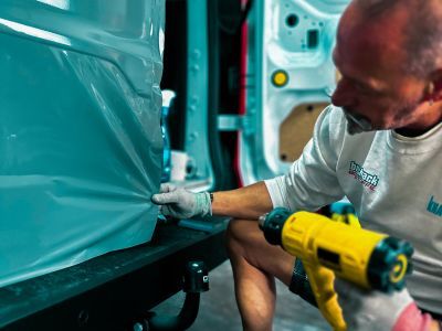 Folie wird mit Hei&szlig;luft auf Fahrzeug geklebt &ndash; zeigt Fahrzeugveredelung durch moderne Werbetechnik