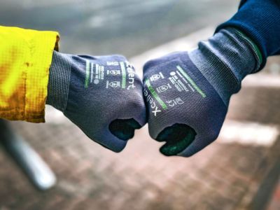 Zwei Personen mit Handschuhen sto&szlig;en F&auml;uste zusammen, symbolisieren Teamgeist, Begr&uuml;&szlig;ung oder Zusammenarbeit