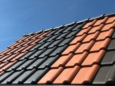 Dach mit Ziegeln in Rot, Grau und Braun unter blauem Himmel zeigt Vielfalt an Materialien f&uuml;r Dachdeckung