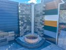 Steinbrunnen mit Wasserbecken vor gemusterter Mauer im Freien, dekoratives Element f&uuml;r Gartenbau sichtbar