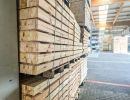Gestapelte Holzplanken in Lagerhalle, geordnetes Material zeigt Vielfalt und Einsatzm&ouml;glichkeiten im Holzbau