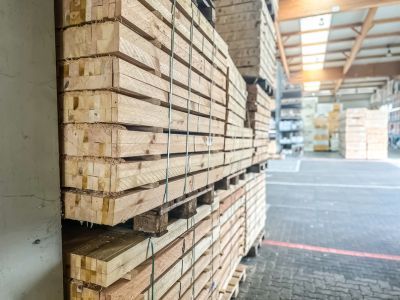 Gestapelte Holzplanken in Lagerhalle, geordnetes Material zeigt Vielfalt und Einsatzm&ouml;glichkeiten im Holzbau