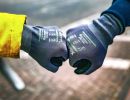 Zwei H&auml;nde mit Arbeitshandschuhen sto&szlig;en F&auml;uste zusammen, symbolisieren Teamarbeit und Arbeitsschutz