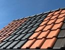 Dach mit Ziegeln in Rot, Grau und Braun unter blauem Himmel zeigt Vielfalt an Materialien f&uuml;r Dachdeckung