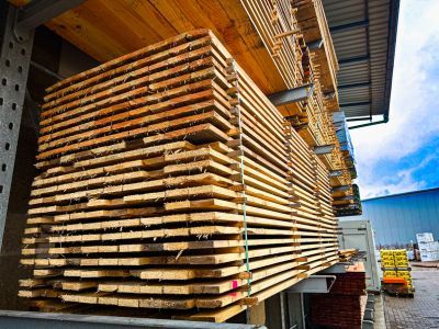 Holzlatten ordentlich gestapelt unter Dach, zeigen Lagerung von Baumaterialien f&uuml;r sp&auml;tere Verwendung
